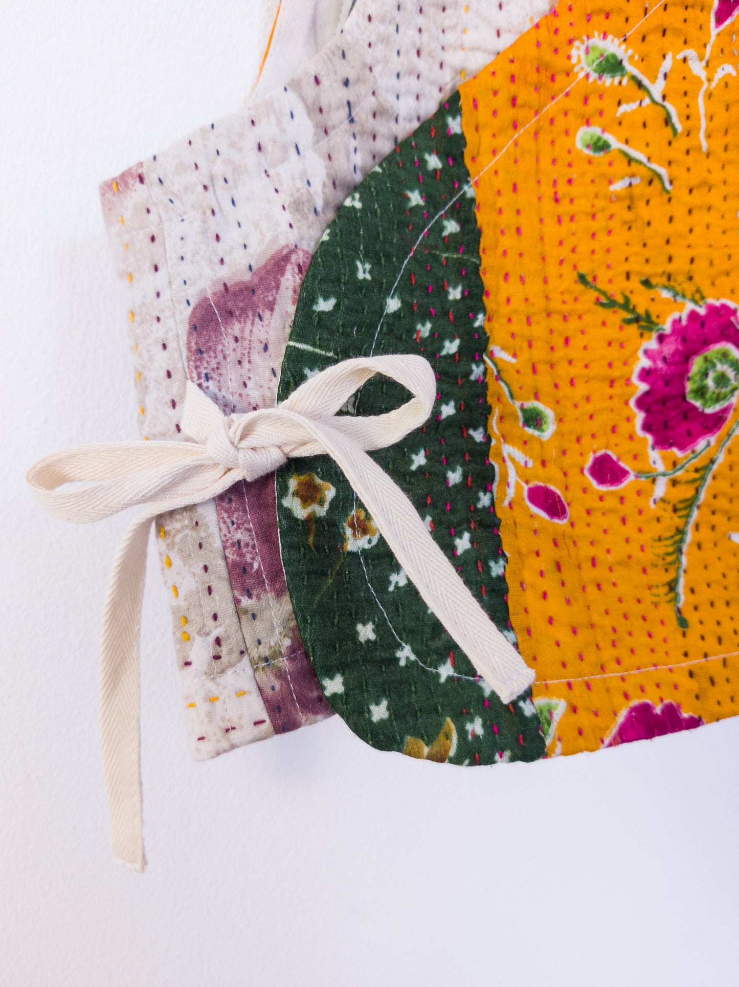 Detailaufnahme der „Flower Patch Club Vest“, zeigt Kantha-Stickerei und Struktur, gebunden mit einer Schleife.