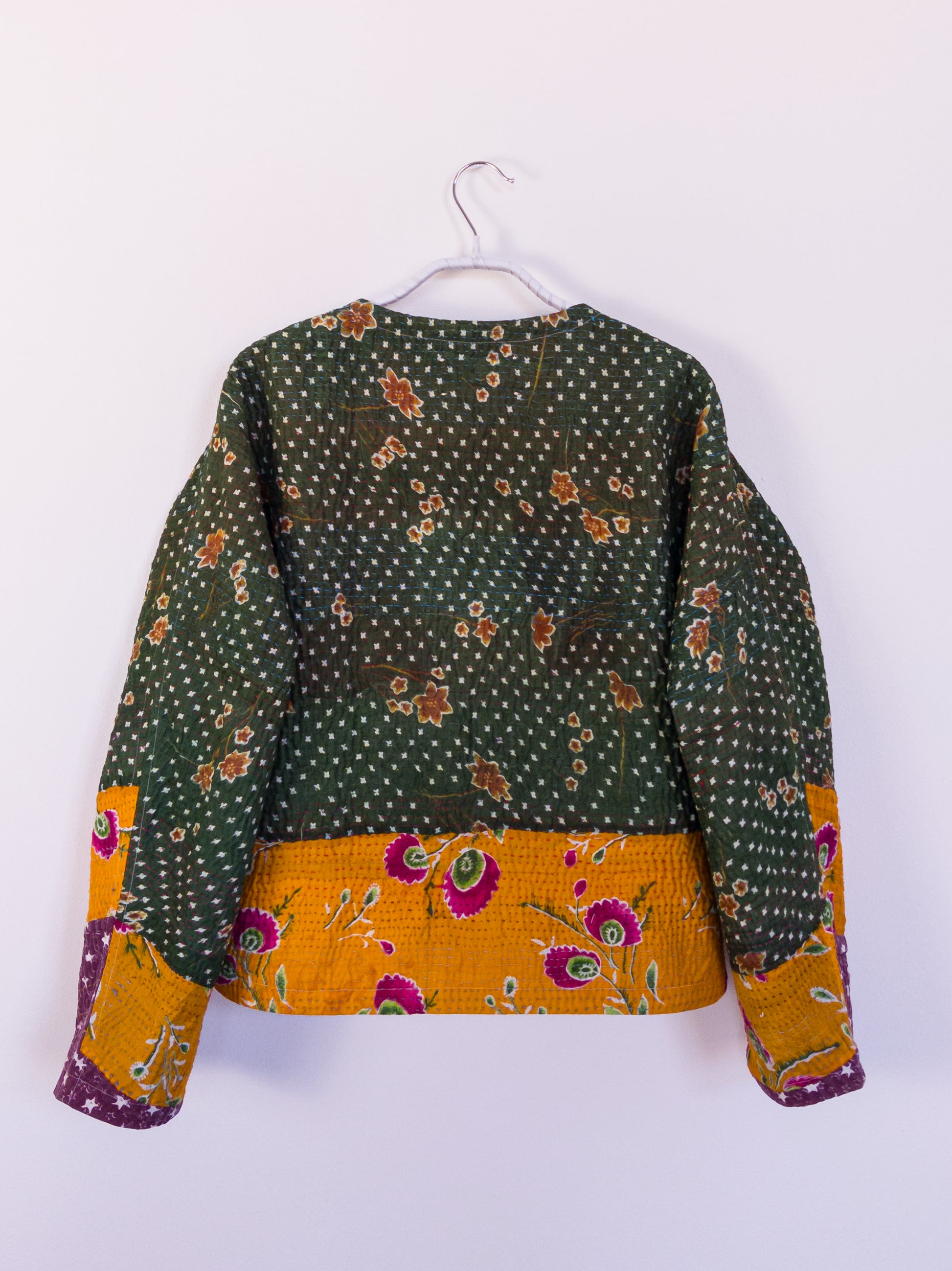 Rückansicht der „Flower Patch Club Jacket“, zeigt das detailreiche Patchwork aus lila, orange und grünen Stoffen.