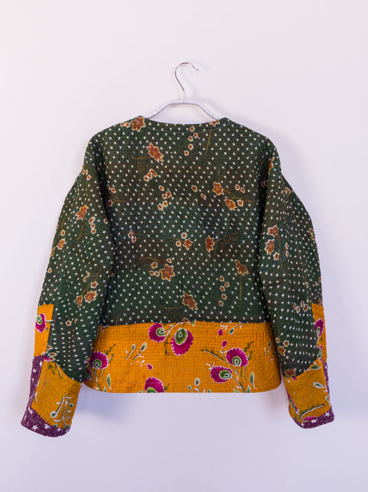 Rückansicht der „Flower Patch Club Jacket“, zeigt das detailreiche Patchwork aus lila, orange und grünen Stoffen.