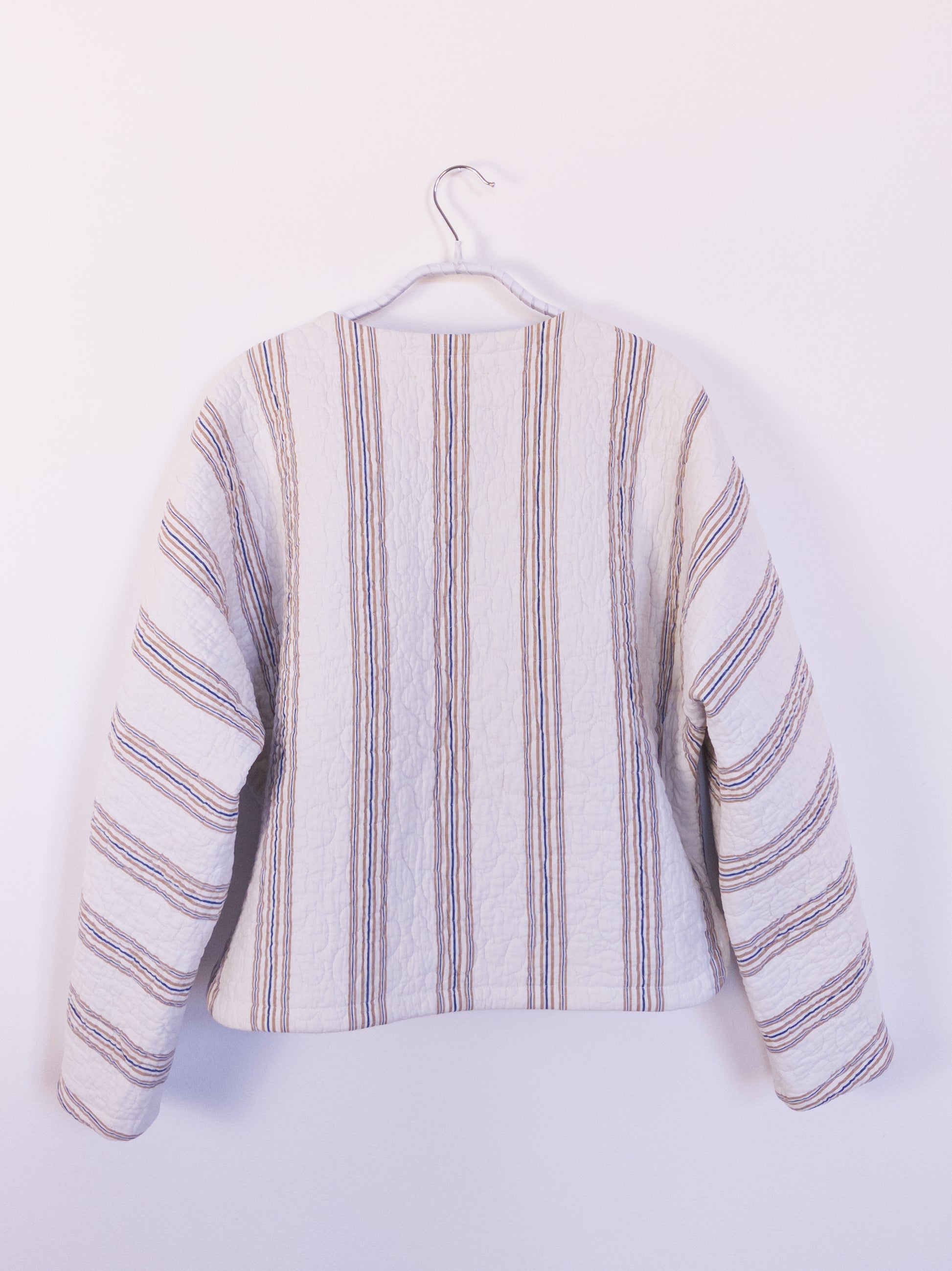 Rückansicht der „Heaven’s Stripe Club Jacket“ mit feinen vertikalen Streifen in Creme, Dunkelblau und Braun.