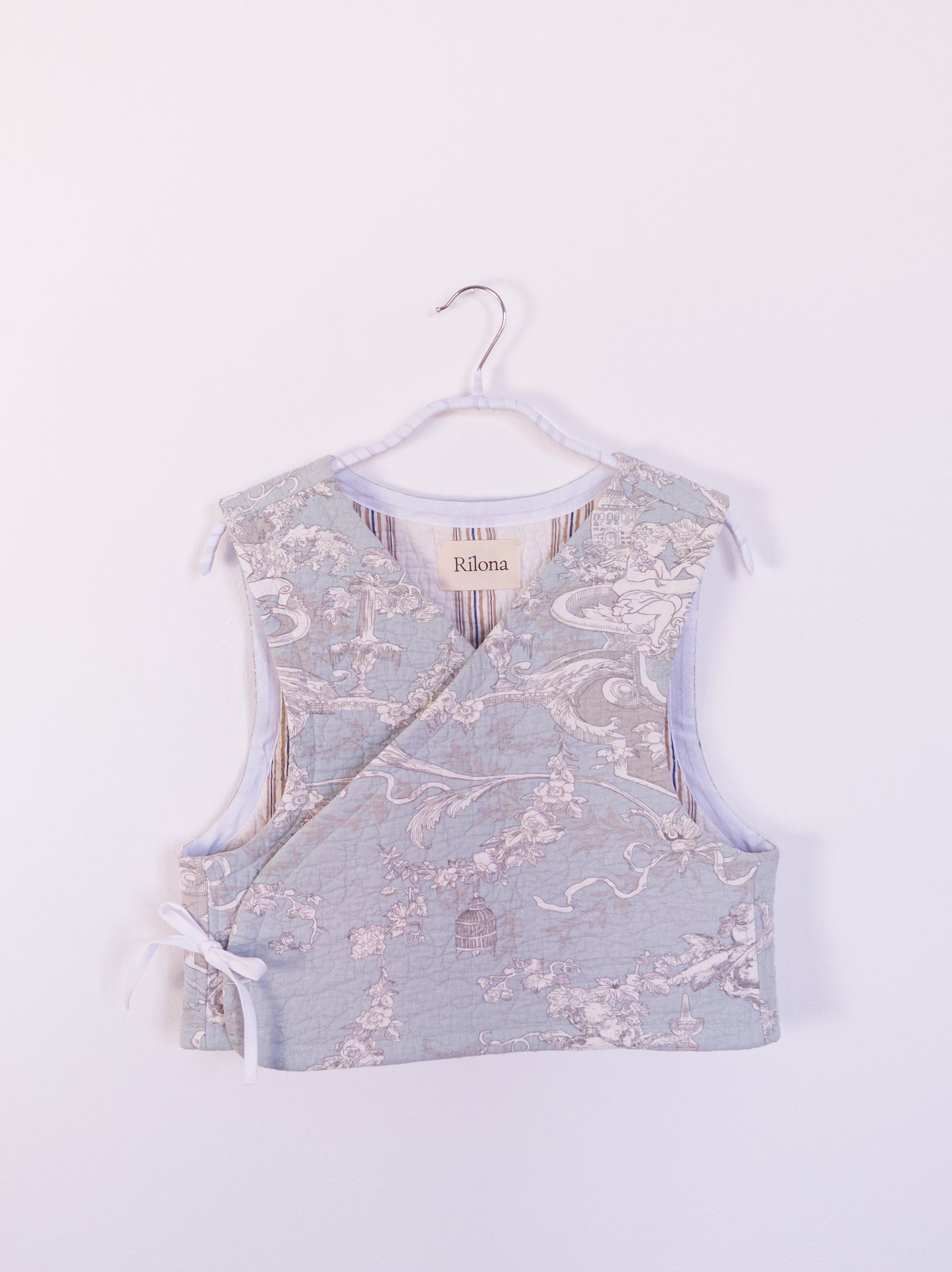 Vorderansicht der handgefertigten „Heaven’s Stripe Club Vest“ aus Baumwolle mit zartblauem Grund und cremefarbenem Engelmuster.