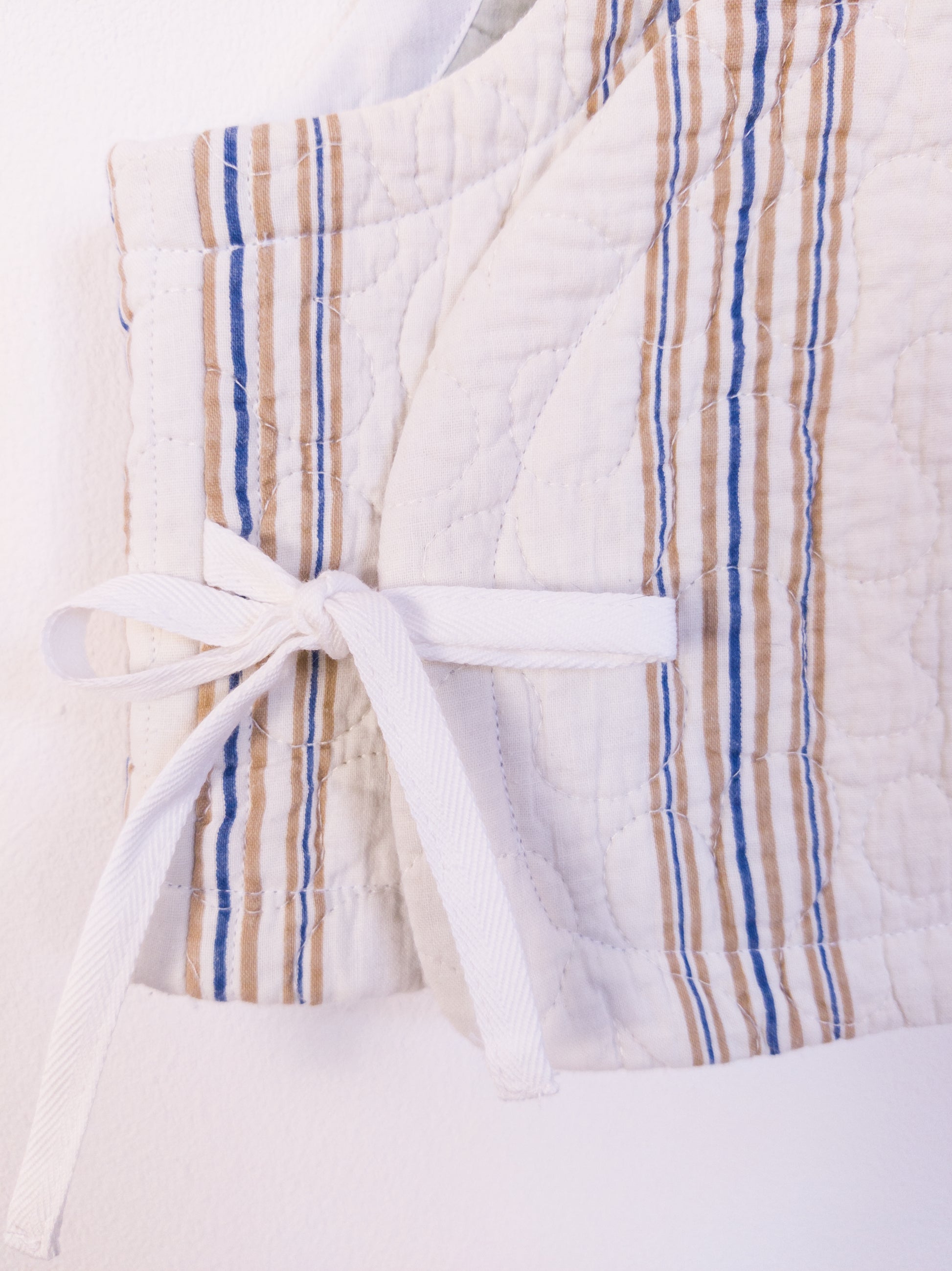 Detailaufnahme der „Heaven’s Stripe Club Vest“, zeigt die strukturierte Baumwolle und das Bindedetail.