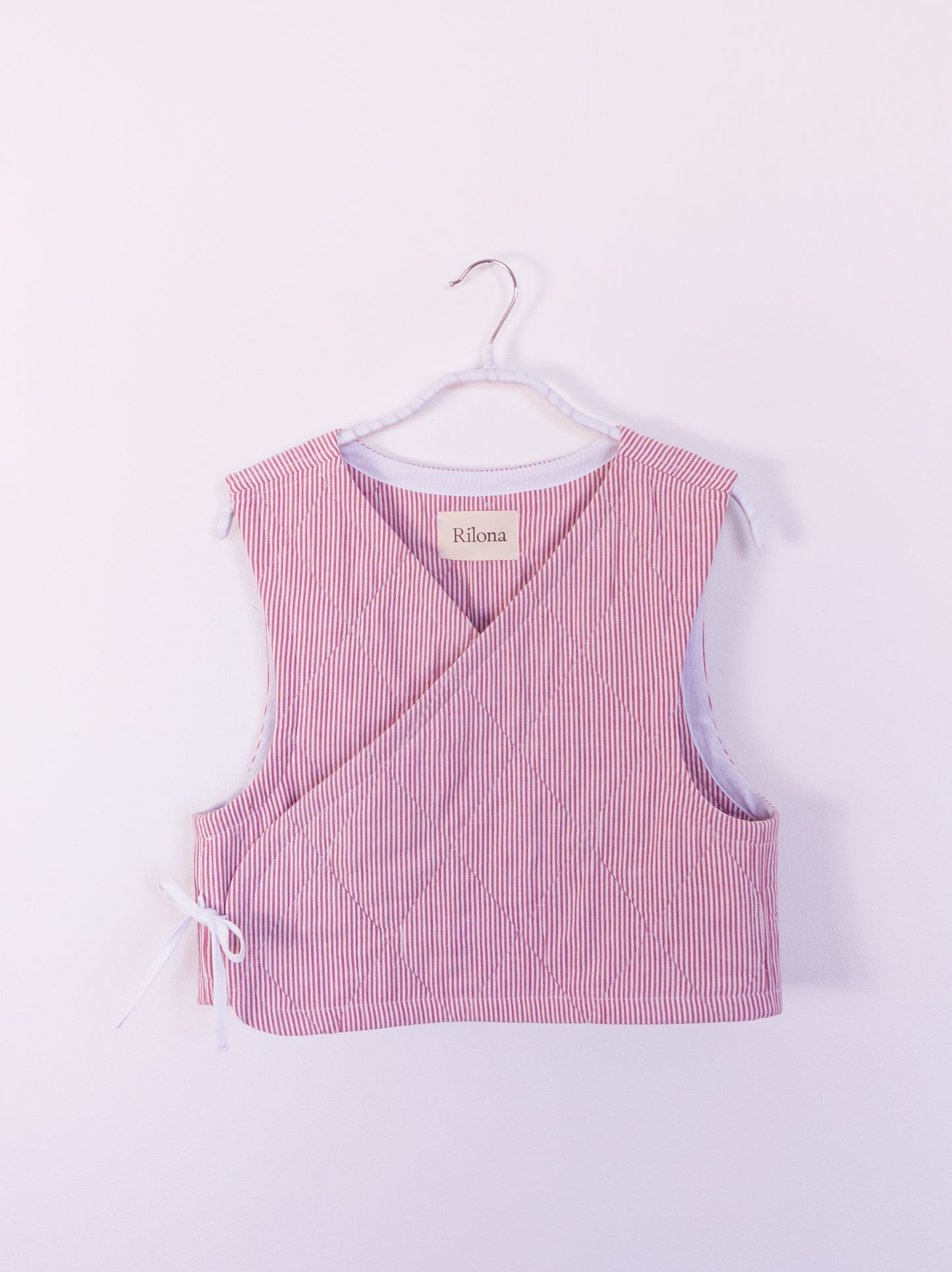 Vorderansicht der handgefertigten „Red Hot Vest“ aus rot-weiß gestreifter Steppdecke mit rautenförmiger Absteppung.