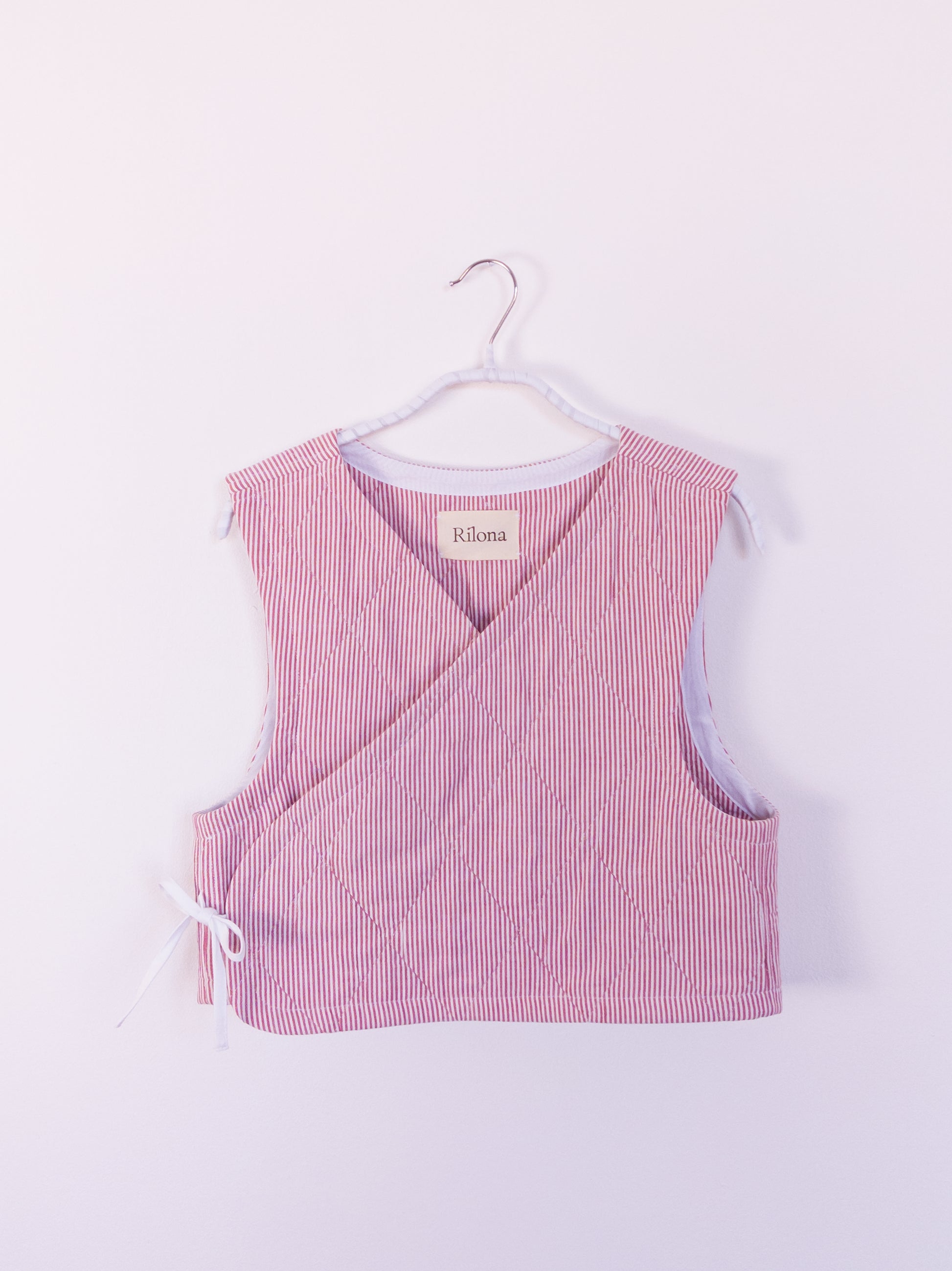 Vorderansicht der handgefertigten „Red Hot Vest“ aus rot-weiß gestreifter Steppdecke mit rautenförmiger Absteppung.