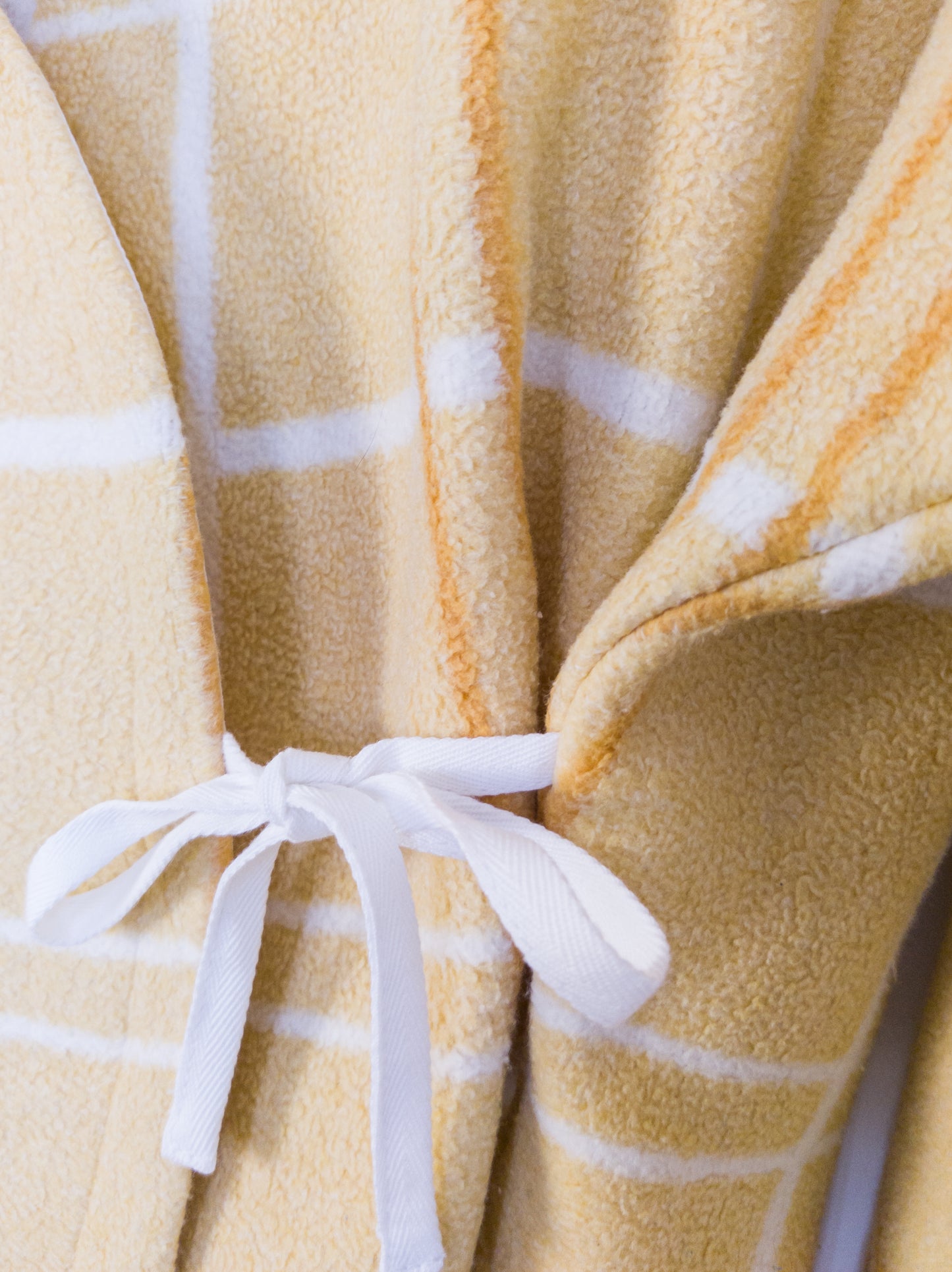 Detailaufnahme der „Sunny Side Up Jacket“, zeigt die flauschige Textur, gebunden mit einer Schleife.