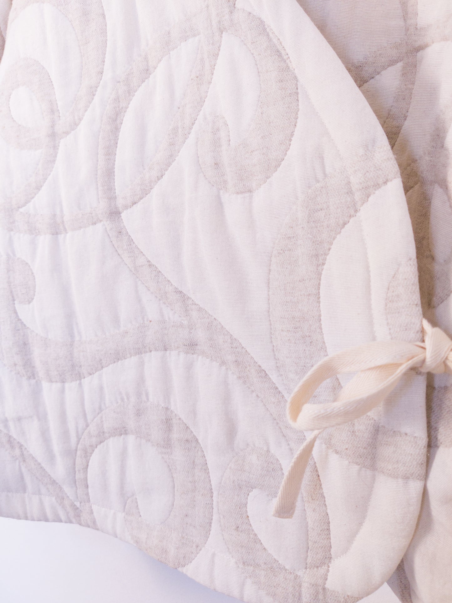 Detailansicht der strukturierten Oberfläche der „The Oatmeal Enthusiast Jacket“ aus weicher, beigefarbener Kunstfaser mit feinen Schlingen, gebunden mit beiger Schleife.