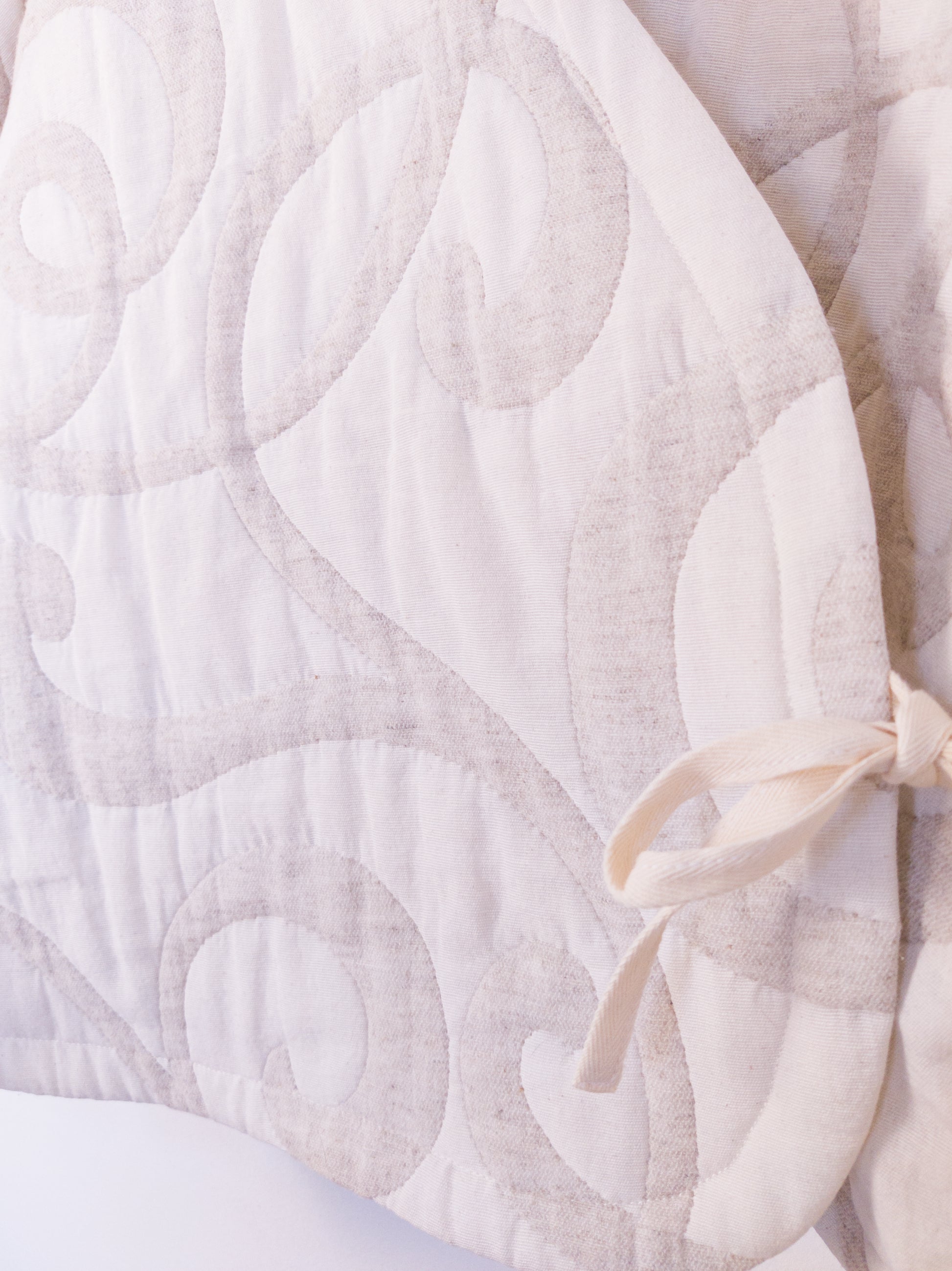 Detailansicht der strukturierten Oberfläche der „The Oatmeal Enthusiast Jacket“ aus weicher, beigefarbener Kunstfaser mit feinen Schlingen, gebunden mit beiger Schleife.