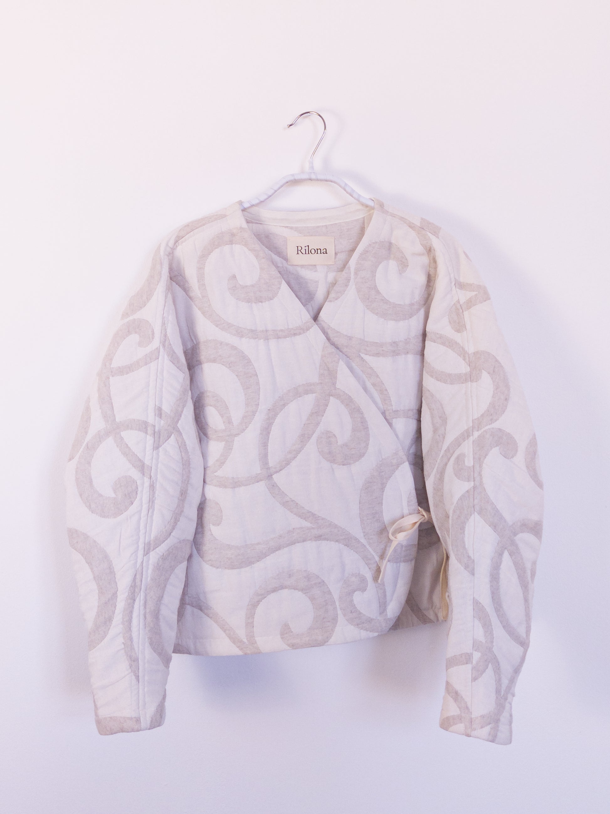 Vorderansicht der handgefertigten „The Oatmeal Enthusiast Jacket“ aus beiger Steppdecke mit feinen Schlingen, auf einem Haken hängend.