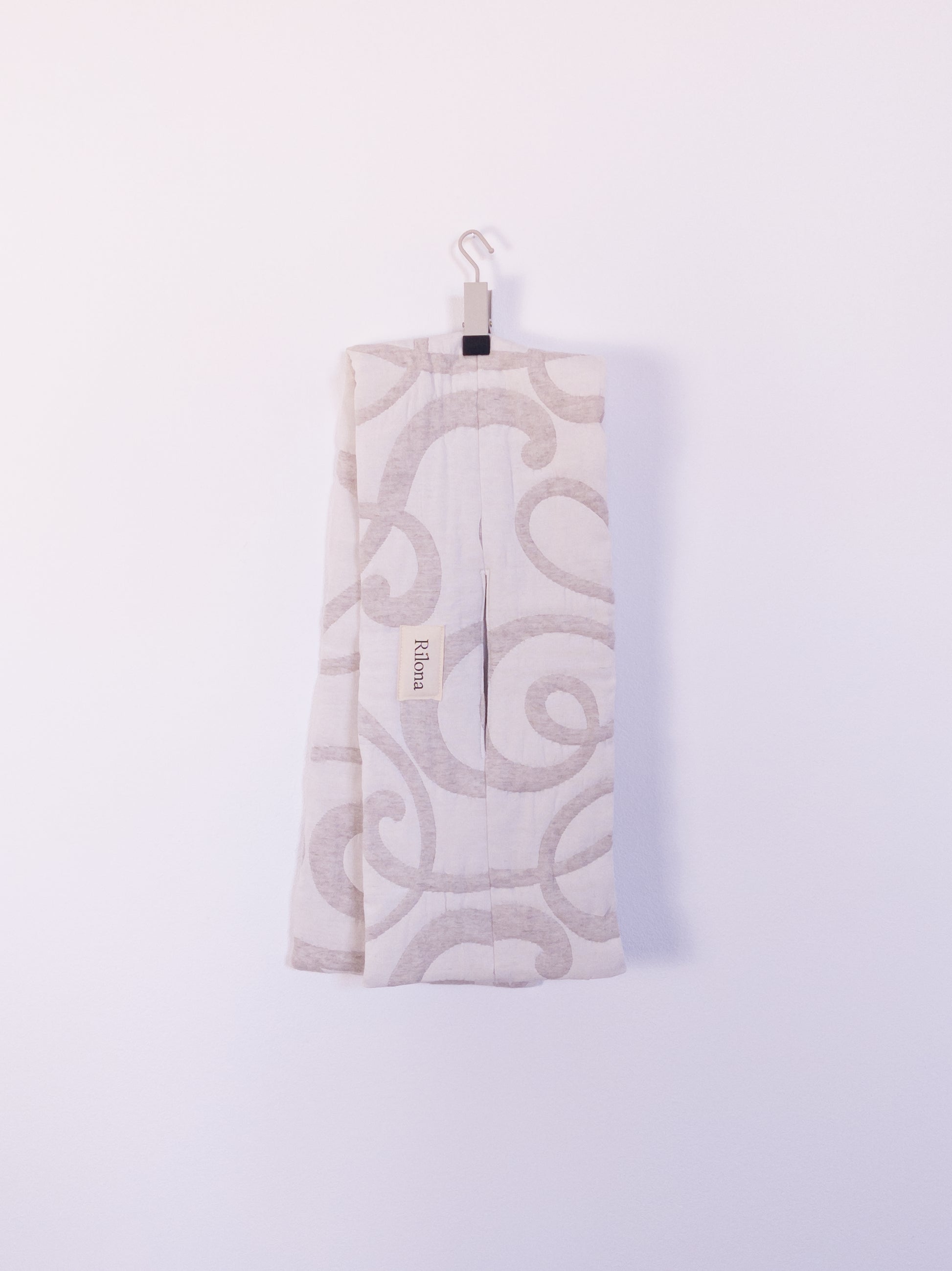 Handgefertigter „The Oatmeal Enthusiast Scarf“ aus beiger Steppdecke mit feinen Schlingen, auf einem Haken hängend.