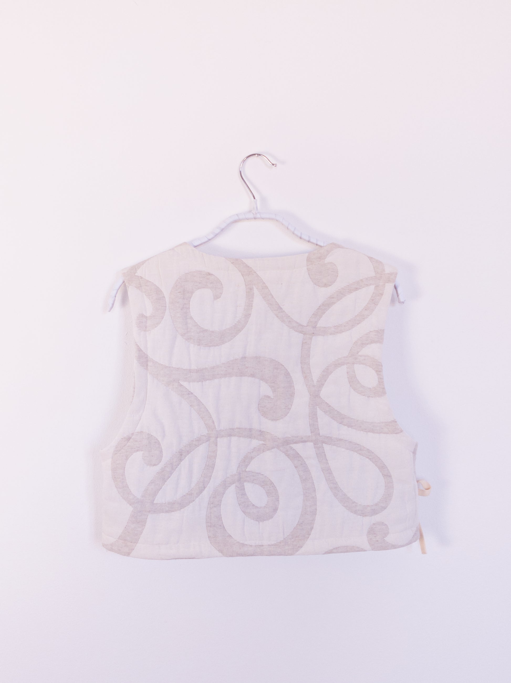 Rückansicht der „The Oatmeal Enthusiast Vest“ aus cremefarbener Steppdecke, zeigt Struktur und handwerkliche Verarbeitung.