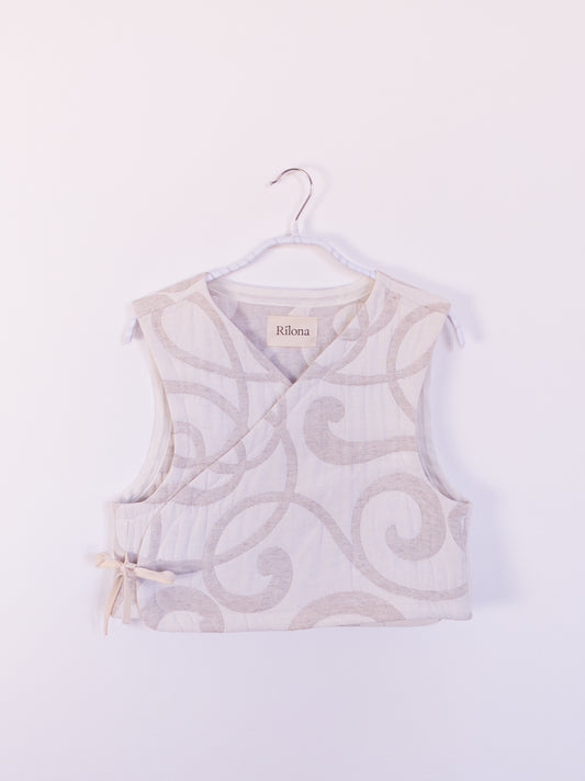 Vorderansicht der handgefertigten „The Oatmeal Enthusiast Vest“ aus beiger Steppdecke mit feinen Schlingen, auf einem Haken hängend.