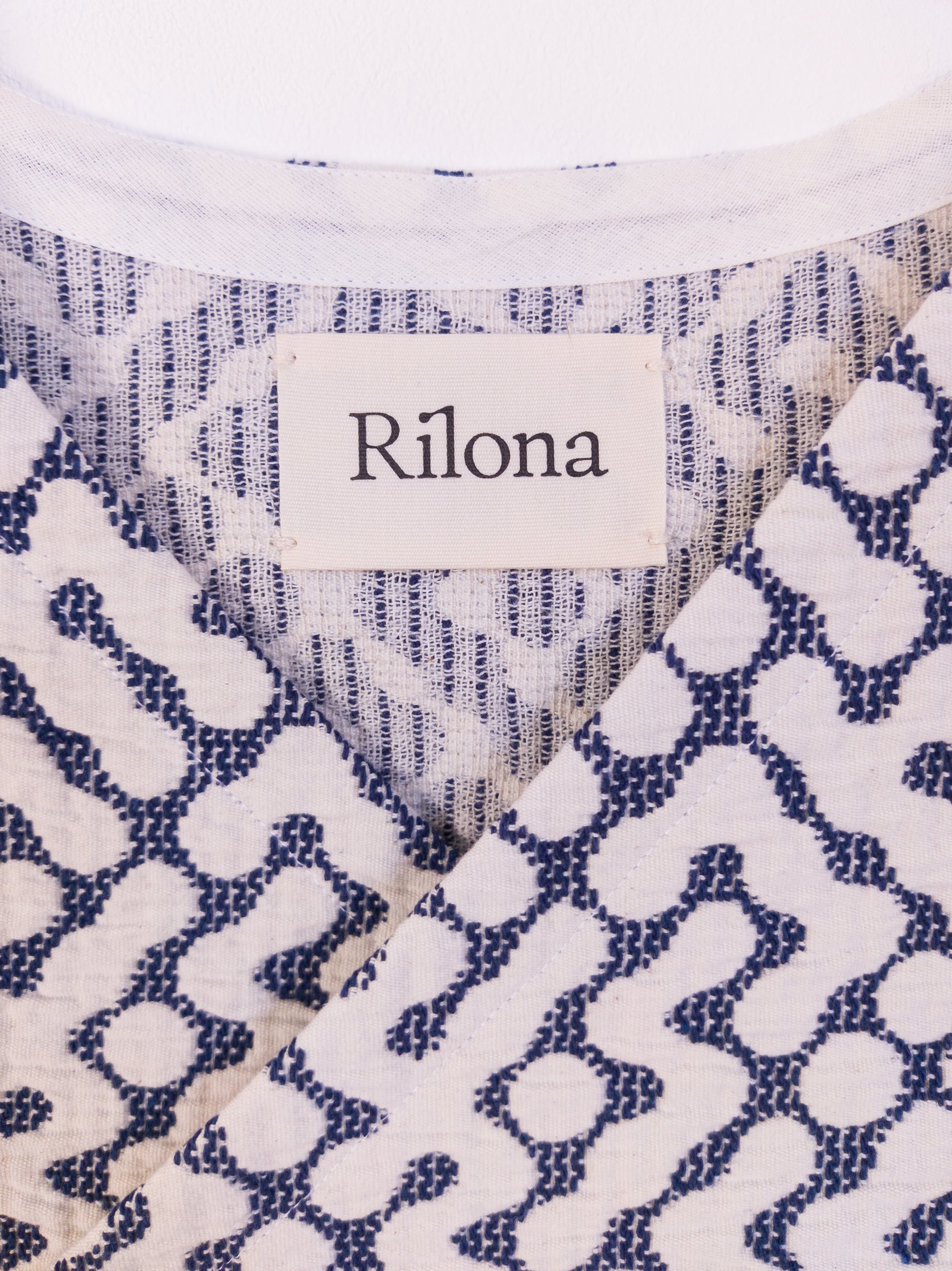 Detailansicht vom Halsloch der handgefertigten „The Orb Awakens Vest“ aus Baumwolle in Blau mit weißem kreisförmigem Muster.